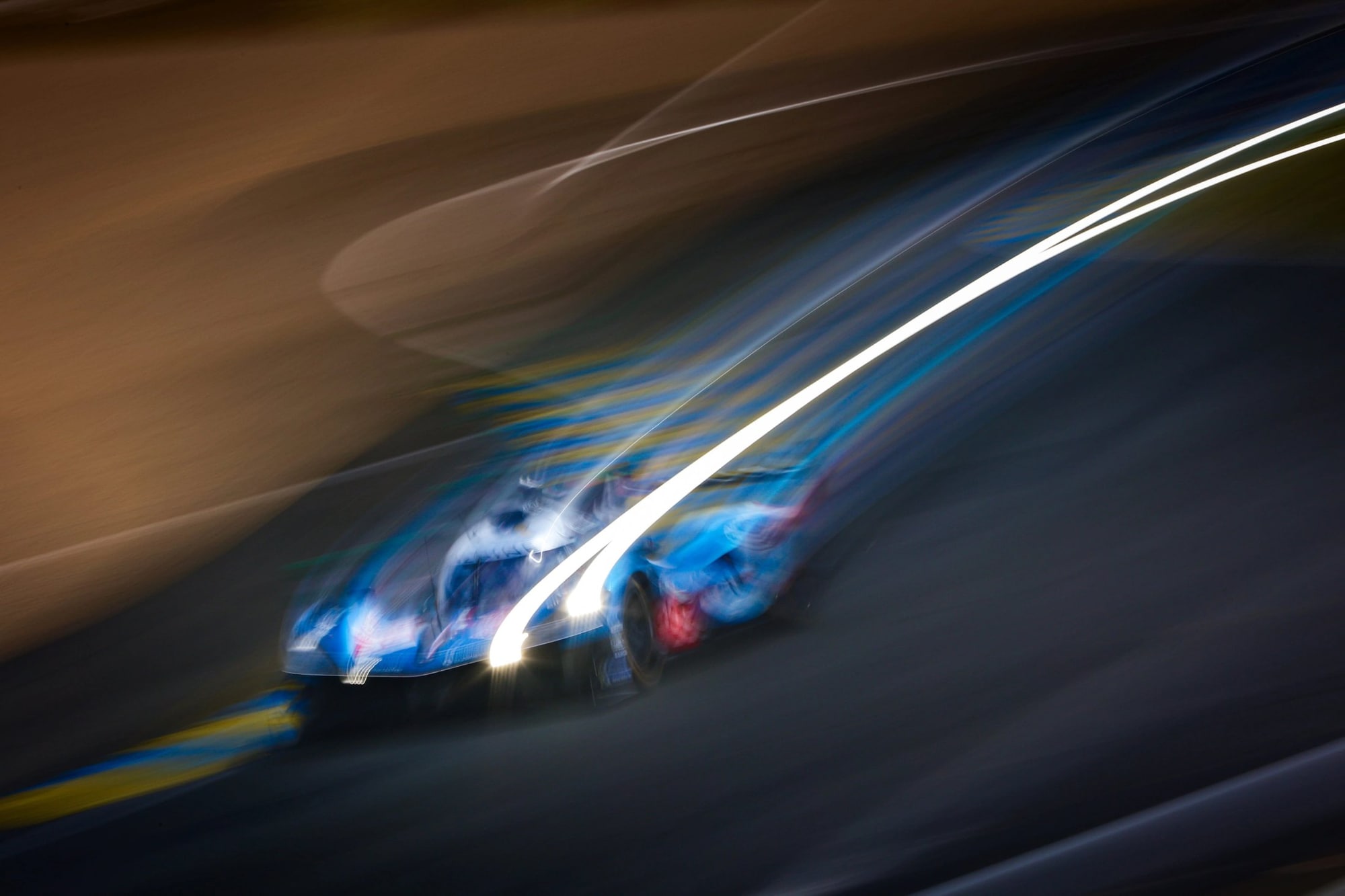 An endurance race car cutting through the night at Le Mans